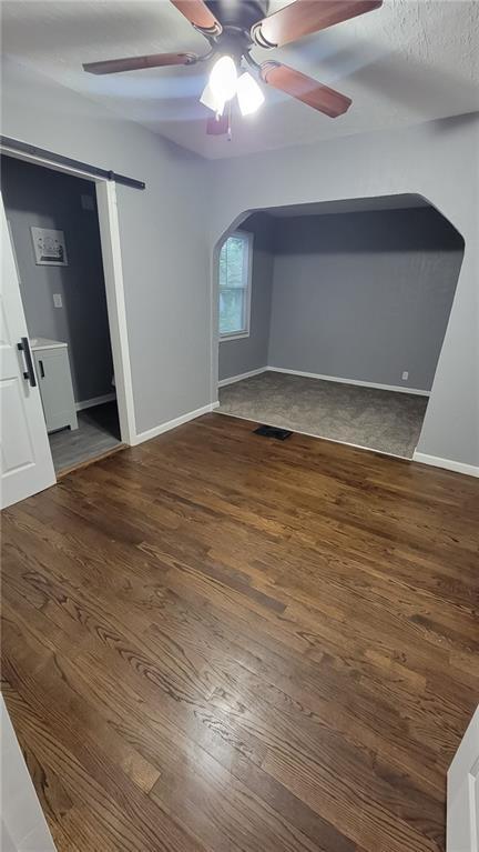 4216 E 67th Ter, Kansas City, MO 64132 - unfurnished living room with arched walkways, a ceiling fan, and wood finished floors