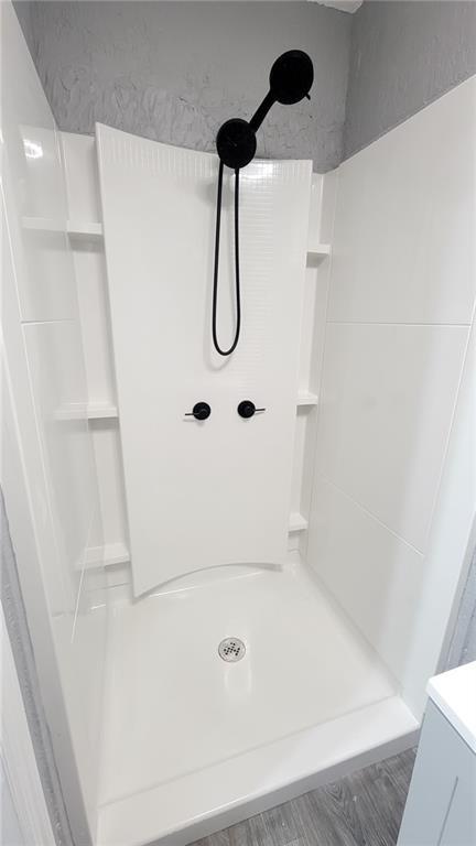 4216 E 67th Ter, Kansas City, MO 64132 - bathroom featuring a shower, wood finished floors, and vanity
