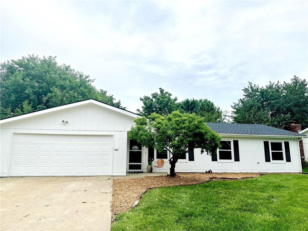 3617 W 24th St, Lawrence, KS 66047 - ranch-style house featuring a front lawn, driveway, a shingled roof, and an attached garage