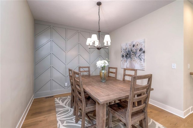 24110 W 95th St, Lenexa, KS 66227 - dining space with light wood finished floors, a chandelier, and a decorative wall