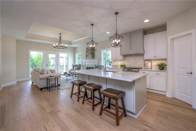 24110 W 95th St, Lenexa, KS 66227 - kitchen with open floor plan, a chandelier, a kitchen breakfast bar, light wood-type flooring, and tasteful backsplash