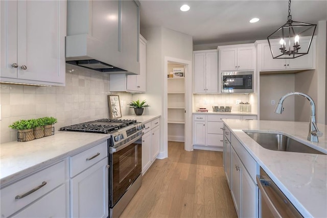 24110 W 95th St, Lenexa, KS 66227 - kitchen with stainless steel appliances, a chandelier, white cabinets, decorative backsplash, and light wood finished floors