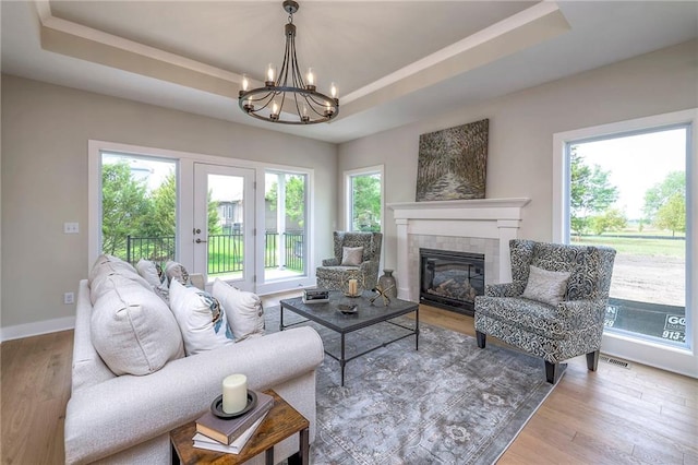 24110 W 95th St, Lenexa, KS 66227 - living area with a tray ceiling, a chandelier, wood finished floors, and a tile fireplace