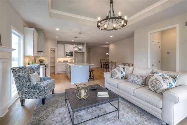 24110 W 95th St, Lenexa, KS 66227 - living area featuring a chandelier, light wood-style floors, a tray ceiling, and recessed lighting