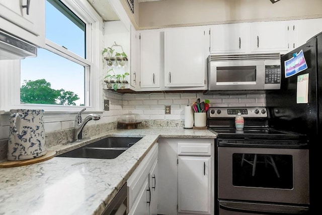 709 S 9th St, Louisburg, KS 66053 - kitchen with appliances with stainless steel finishes, white cabinets, backsplash, and healthy amount of natural light