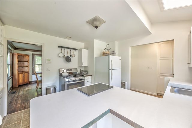 11 W 70th St, Kansas City, MO 64113 - kitchen with freestanding refrigerator, stainless steel range with gas stovetop, a peninsula, white cabinetry, and light countertops