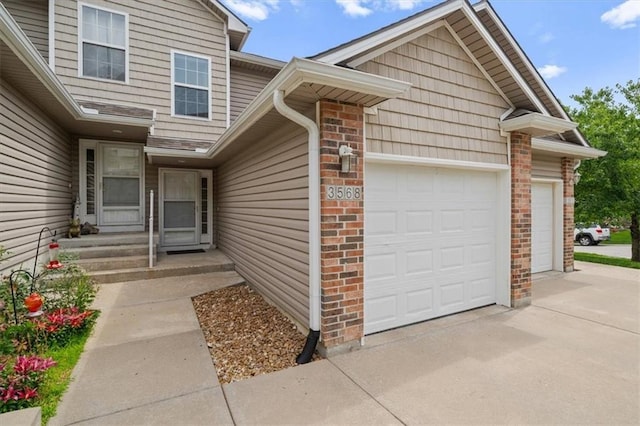 3568 NE Austin Dr, Lees Summit, MO 64064 - view of exterior entry featuring a garage, brick siding, and concrete driveway