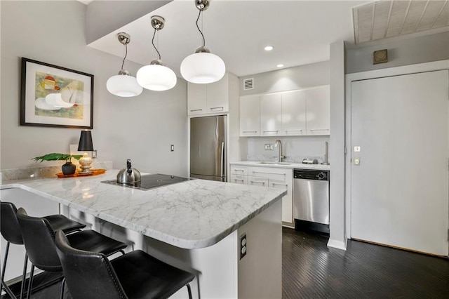 4545 Wornall Rd Unit Le4, Kansas City, MO 64111 - kitchen featuring stainless steel appliances, a peninsula, white cabinetry, a kitchen bar, and recessed lighting