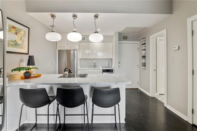 4545 Wornall Rd Unit Le4, Kansas City, MO 64111 - kitchen featuring stainless steel refrigerator, a peninsula, a kitchen breakfast bar, white cabinetry, and decorative light fixtures