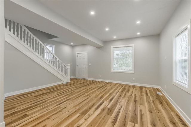410 Kensington Ave, Kansas City, MO 64124 - unfurnished living room featuring light wood finished floors, stairs, healthy amount of natural light, and recessed lighting