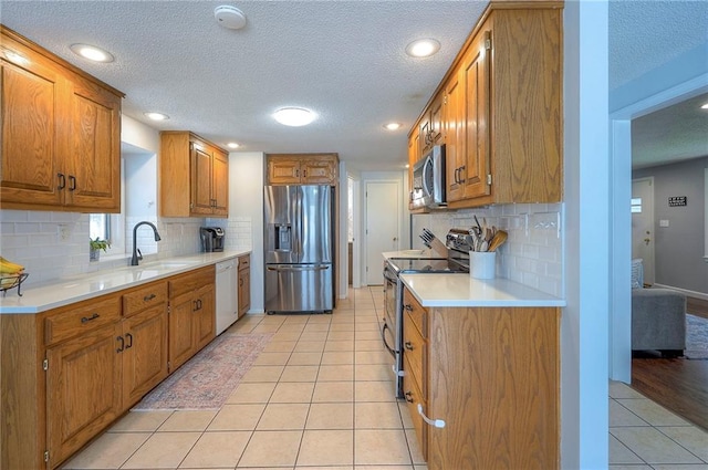11325 W 54th St, Shawnee, KS 66203 - kitchen featuring stainless steel appliances, brown cabinets, a textured ceiling, light countertops, and light tile patterned flooring