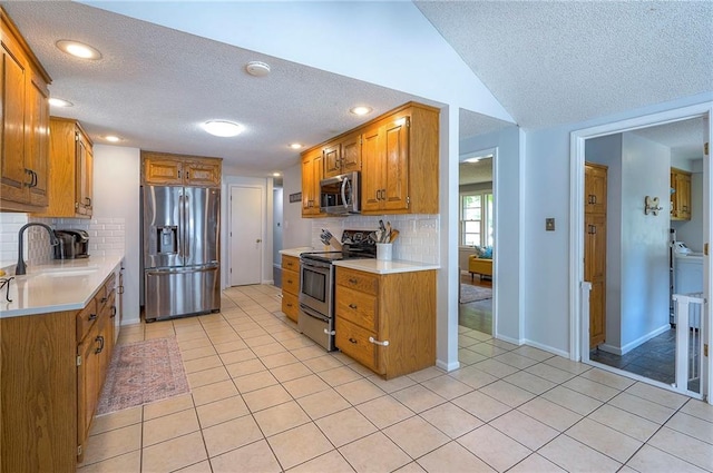 11325 W 54th St, Shawnee, KS 66203 - kitchen featuring appliances with stainless steel finishes, brown cabinets, a textured ceiling, light countertops, and lofted ceiling