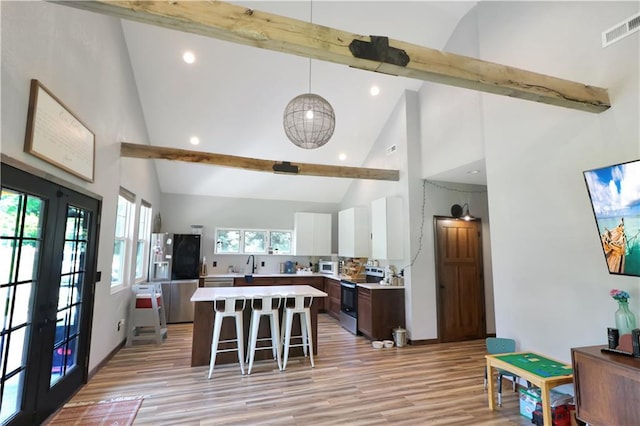 501 NW 101st Rd, Warrensburg, MO 64093 - kitchen featuring stainless steel appliances, a kitchen bar, beam ceiling, light countertops, and light wood-style flooring