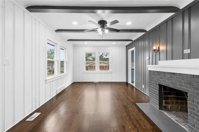 6806 N Brookside Rd, Pleasant Valley, MO 64068 - unfurnished living room featuring wood finished floors, beamed ceiling, a ceiling fan, a brick fireplace, and a decorative wall