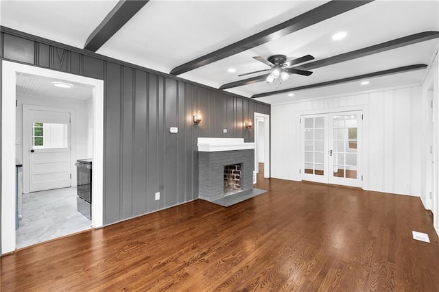 6806 N Brookside Rd, Pleasant Valley, MO 64068 - unfurnished living room featuring beamed ceiling, ceiling fan, french doors, a fireplace, and wood finished floors