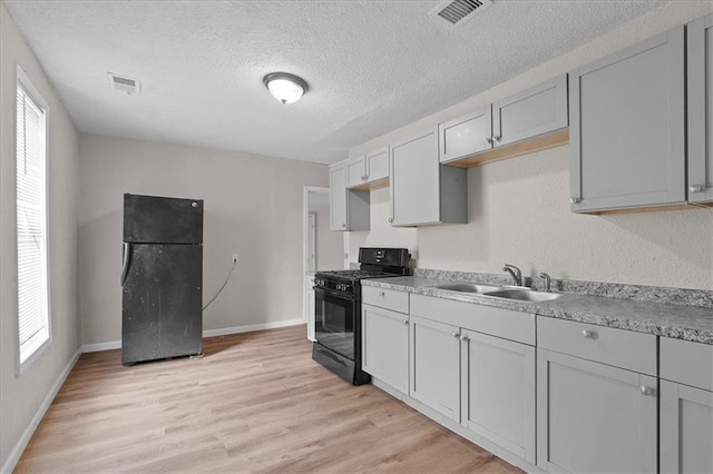 1646 Bennington Ave, Kansas City, MO 64126 - kitchen with black appliances, plenty of natural light, light wood-style floors, and a textured ceiling