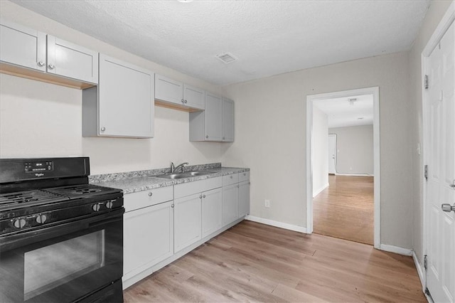 1646 Bennington Ave, Kansas City, MO 64126 - kitchen featuring black gas stove, light wood-style floors, light countertops, and a textured ceiling