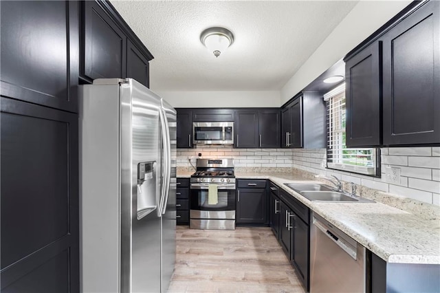 3005 Elmira Ct, Independence, MO 64057 - kitchen featuring stainless steel appliances, decorative backsplash, light countertops, light wood finished floors, and a textured ceiling