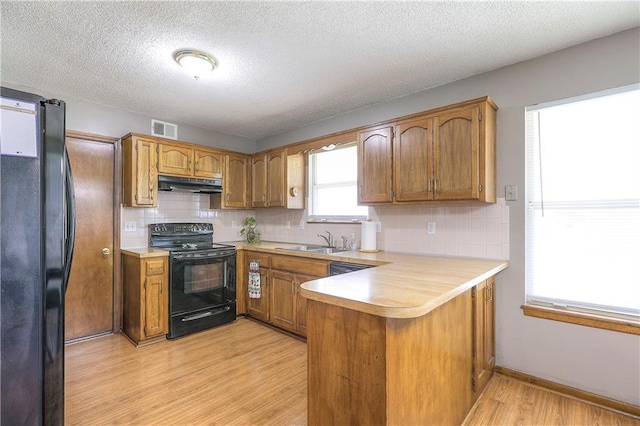 1705 N Jones Ct, Independence, MO 64056 - kitchen with black appliances, under cabinet range hood, a peninsula, light countertops, and a textured ceiling