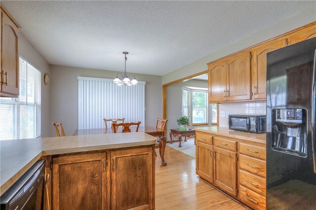 1705 N Jones Ct, Independence, MO 64056 - kitchen featuring black appliances, a chandelier, light countertops, plenty of natural light, and a textured ceiling