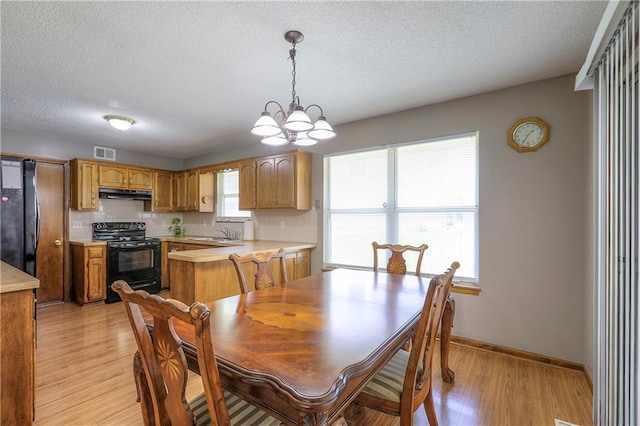 1705 N Jones Ct, Independence, MO 64056 - dining space with light wood-style floors, a textured ceiling, and a chandelier