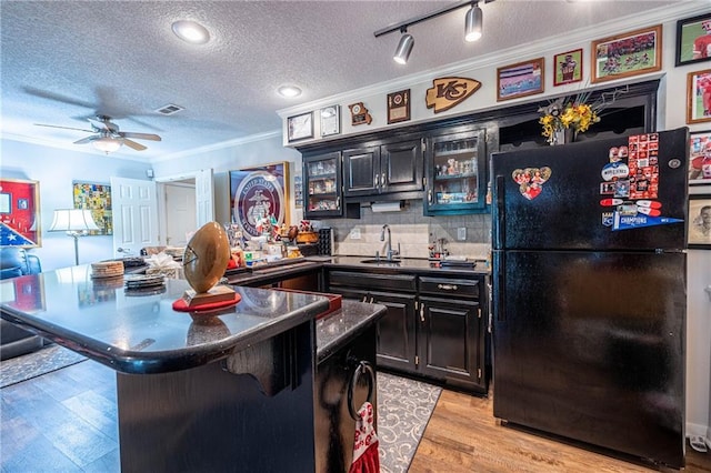 5118 SW Pelican Pt, Lees Summit, MO 64082 - kitchen with freestanding refrigerator, ornamental molding, a textured ceiling, dark countertops, and light wood finished floors