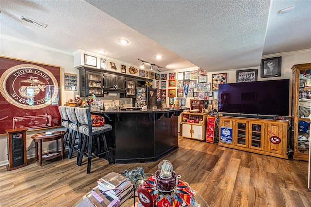 5118 SW Pelican Pt, Lees Summit, MO 64082 - living room featuring a textured ceiling, bar area, wood finished floors, and ornamental molding