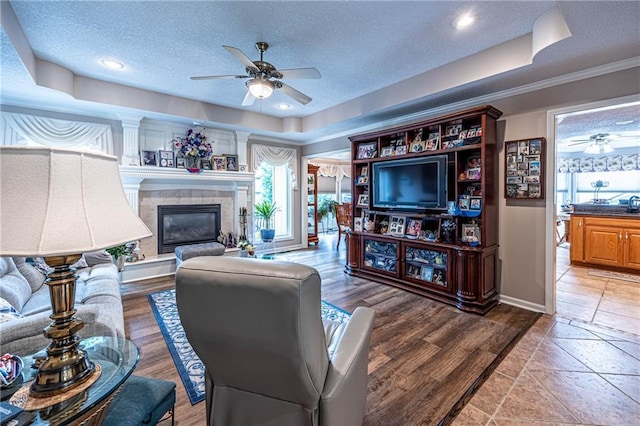 5118 SW Pelican Pt, Lees Summit, MO 64082 - living room featuring ceiling fan, a textured ceiling, a tile fireplace, and wood finished floors