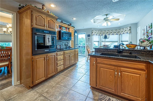 5118 SW Pelican Pt, Lees Summit, MO 64082 - kitchen with black appliances, dark stone counters, brown cabinetry, a ceiling fan, and a textured ceiling