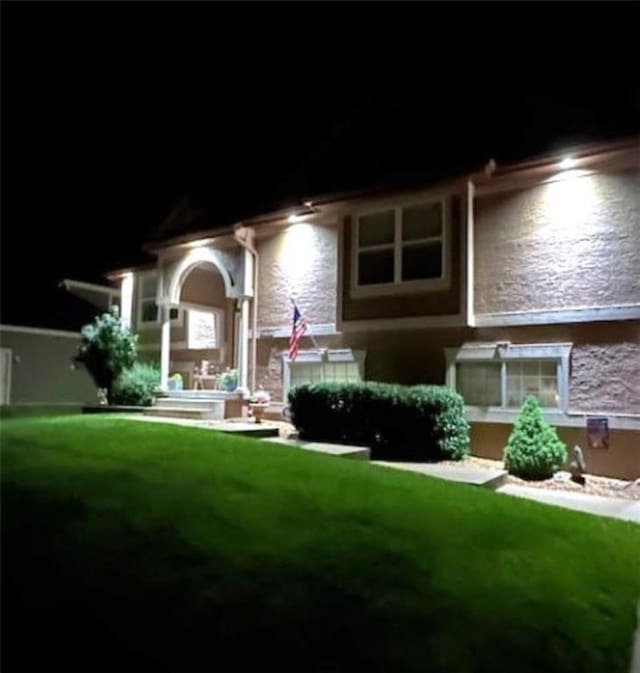 5118 SW Pelican Pt, Lees Summit, MO 64082 - back of house at twilight with a lawn, stucco siding, and stone siding