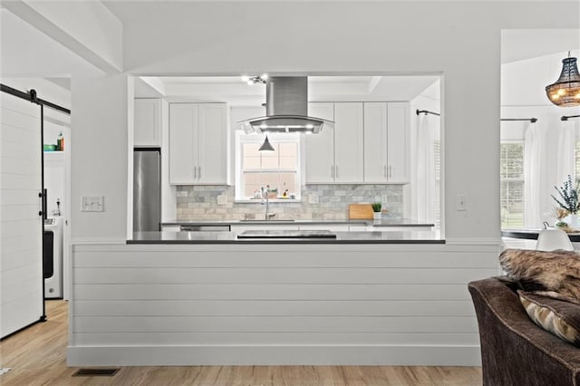 2421 NW Acorn Dr, Blue Springs, MO 64014 - kitchen with a barn door, white cabinetry, ventilation hood, and tasteful backsplash