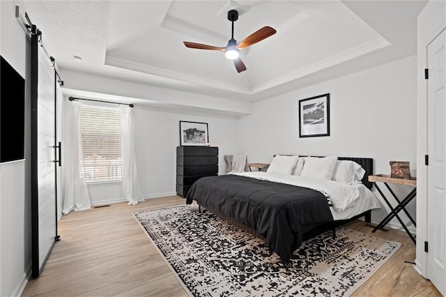 2421 NW Acorn Dr, Blue Springs, MO 64014 - bedroom featuring a raised ceiling, a barn door, light wood-style floors, and ceiling fan