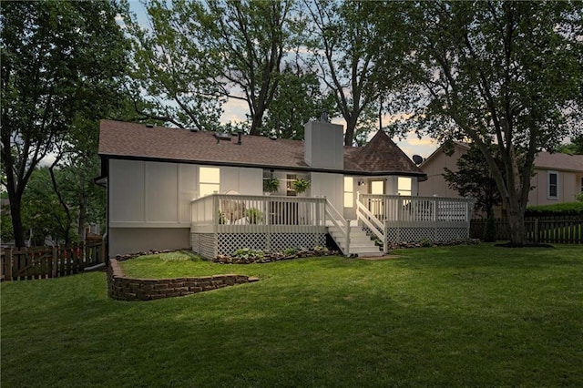 2421 NW Acorn Dr, Blue Springs, MO 64014 - back of property at dusk featuring a fenced backyard, a chimney, a wooden deck, and a shingled roof