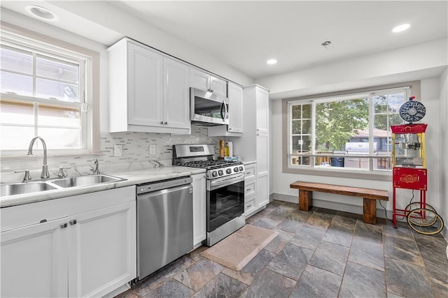 6101 E 107th St, Kansas City, MO 64134 - kitchen featuring appliances with stainless steel finishes, stone tile floors, white cabinets, plenty of natural light, and recessed lighting