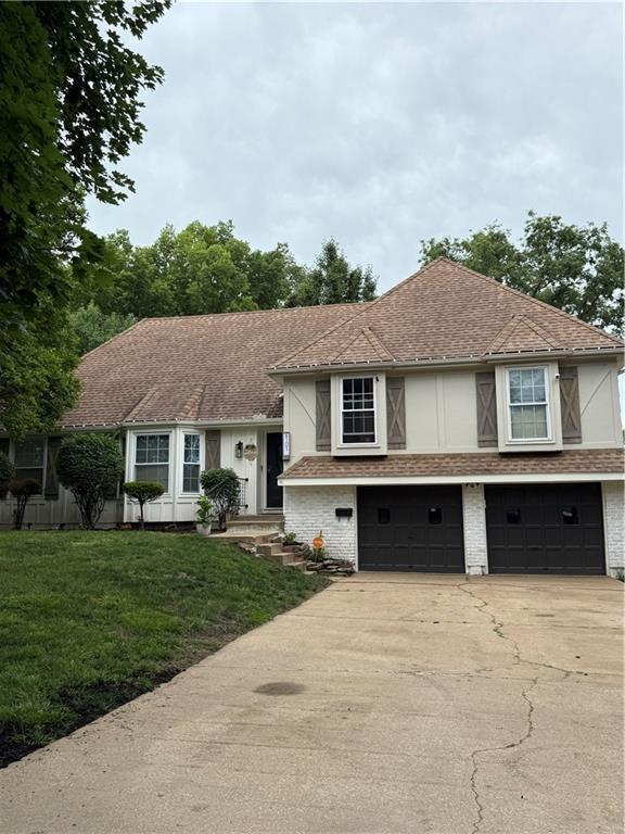 6101 E 107th St, Kansas City, MO 64134 - tri-level home featuring a garage, concrete driveway, a front yard, and brick siding