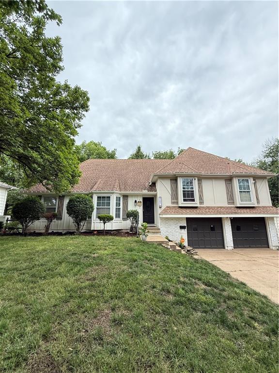 6101 E 107th St, Kansas City, MO 64134 - tri-level home with a garage, concrete driveway, and a front lawn