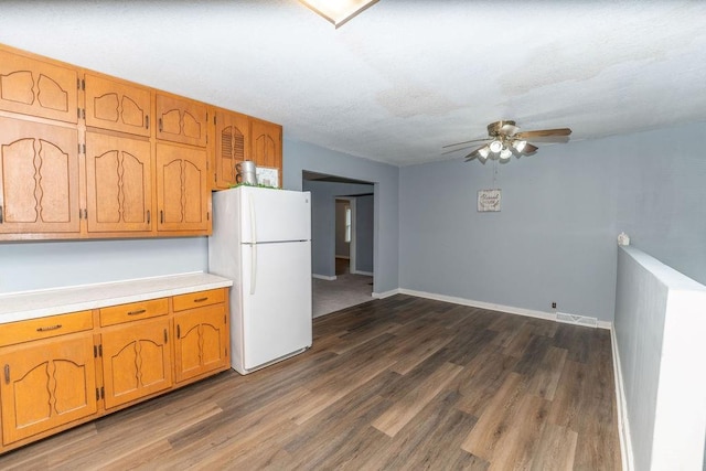 103 N Missouri St, Adrian, MO 64720 - kitchen with freestanding refrigerator, ceiling fan, dark wood-style floors, light countertops, and brown cabinets