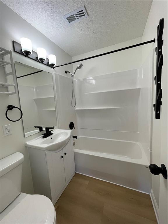 10818-10820 W 57th St, Shawnee, KS 66203 - bathroom with a textured ceiling, shower / bath combination, wood finished floors, and vanity