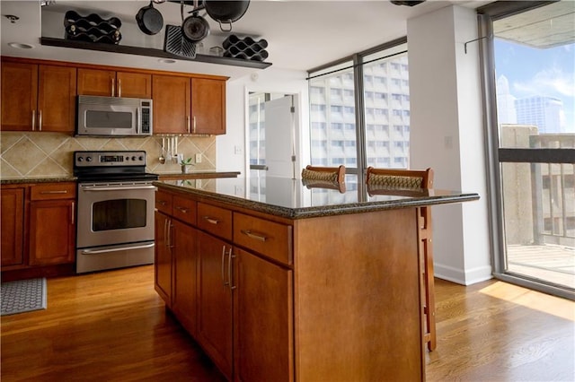 600 Admiral Blvd Unit 1505, Kansas City, MO 64106 - kitchen featuring appliances with stainless steel finishes, wood finished floors, decorative backsplash, and dark stone counters