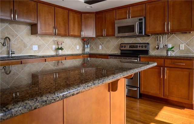 600 Admiral Blvd Unit 1505, Kansas City, MO 64106 - kitchen featuring appliances with stainless steel finishes, brown cabinetry, dark stone countertops, and wood finished floors