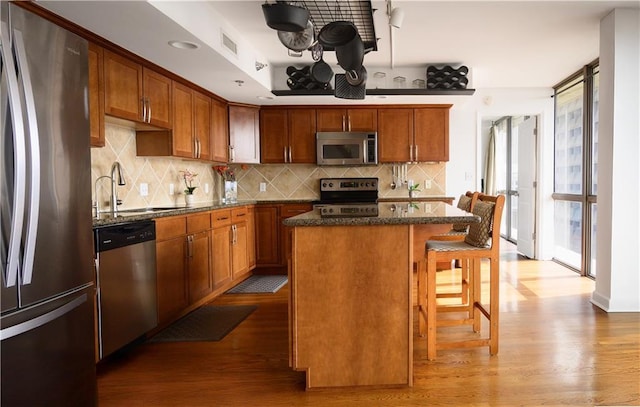 600 Admiral Blvd Unit 1505, Kansas City, MO 64106 - kitchen with stainless steel appliances, a center island, wood finished floors, a kitchen bar, and tasteful backsplash