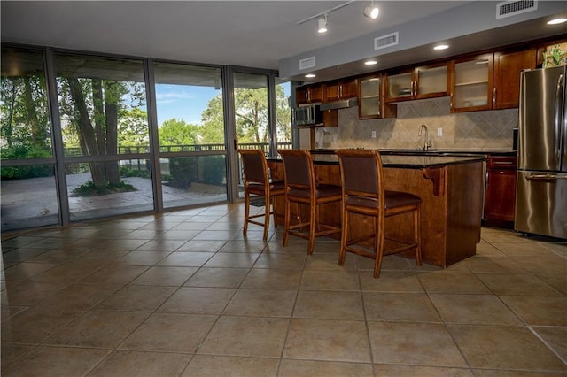 600 Admiral Blvd Unit 1505, Kansas City, MO 64106 - bar area featuring stainless steel appliances, backsplash, light tile patterned floors, under cabinet range hood, and expansive windows