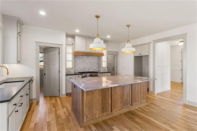 6000 El Monte St, Fairway, KS 66205 - kitchen with stainless steel appliances, light wood-style floors, dark stone countertops, tasteful backsplash, and a center island