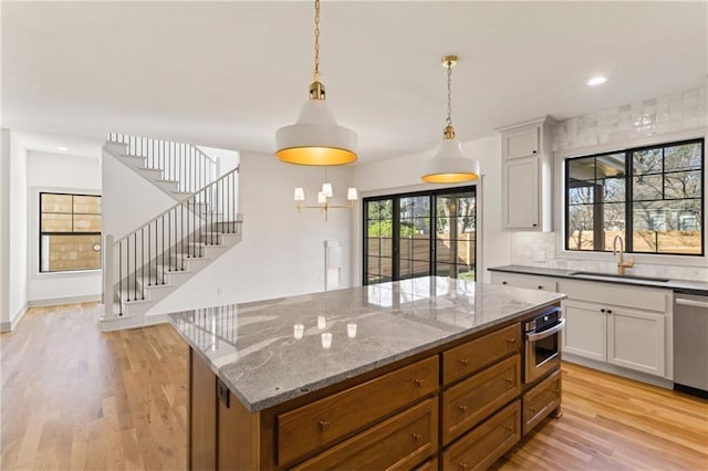 6000 El Monte St, Fairway, KS 66205 - kitchen with stainless steel appliances, light wood-type flooring, a center island, white cabinetry, and light stone countertops