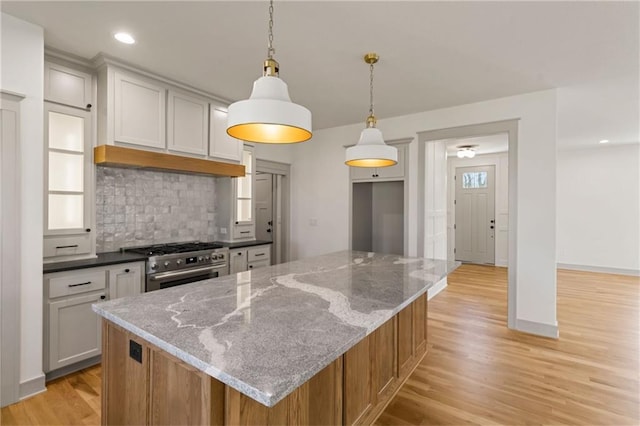 6000 El Monte St, Fairway, KS 66205 - kitchen with high end stainless steel range oven, tasteful backsplash, light wood-type flooring, light stone countertops, and pendant lighting