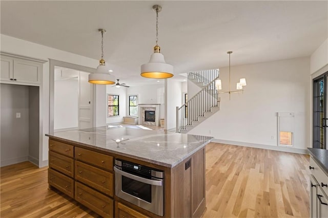 6000 El Monte St, Fairway, KS 66205 - kitchen with light wood-style flooring, a glass covered fireplace, hanging light fixtures, light stone countertops, and stainless steel oven