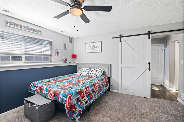 4416 Broadway Ter, Leavenworth, KS 66048 - bedroom featuring a textured ceiling, a barn door, carpet flooring, and a ceiling fan