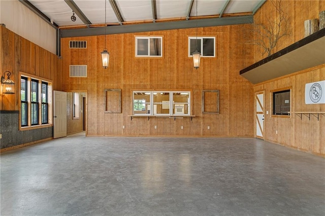 204 E Casey Rd, Lone Jack, MO 64070 - unfurnished living room with a high ceiling, healthy amount of natural light, concrete flooring, and wood walls
