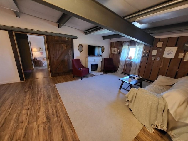 204 E Casey Rd, Lone Jack, MO 64070 - living room featuring beam ceiling, wood finished floors, a barn door, and a fireplace with raised hearth