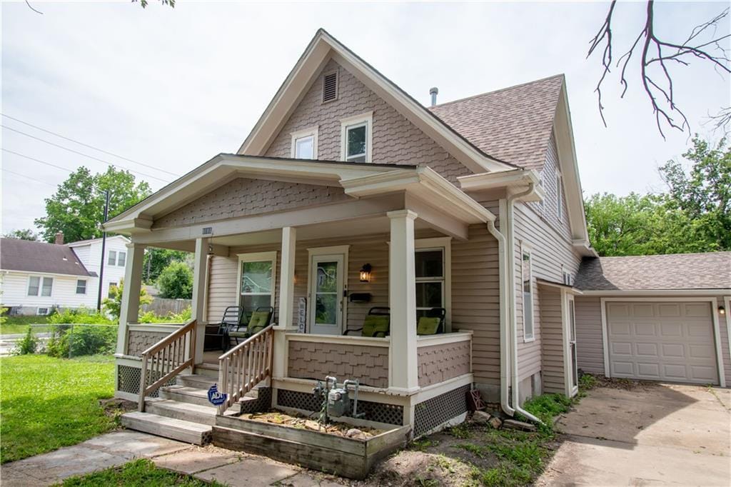1193 SW Jewell Ave, Topeka, KS 66604 - view of front of house featuring a porch, driveway, a shingled roof, and a garage